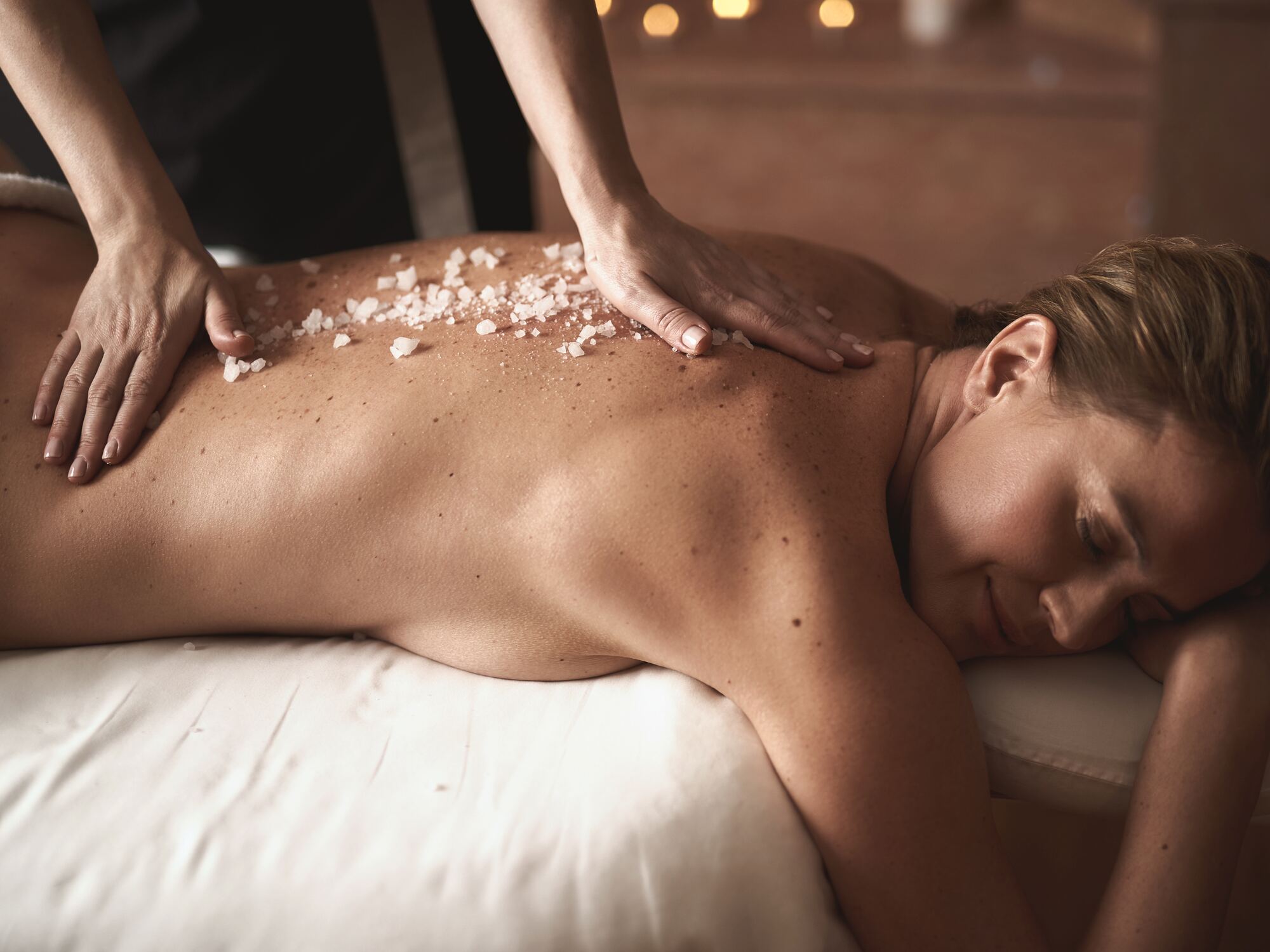 Bodyscrub met zout en kruiden op de rug van een cliënt